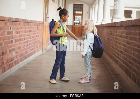 Sorridendo gli alunni tenendo le mani sul corridoio Foto Stock
