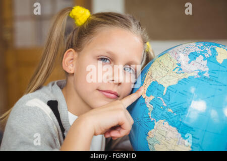 Carino allievo puntando sul globo terrestre in una classe Foto Stock