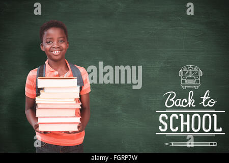 Immagine composita di carino piccolo ragazzo il trasporto di libri in biblioteca Foto Stock