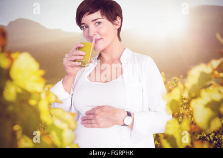 Immagine composita del ritratto di felice donna incinta di bere succo di arancia Foto Stock