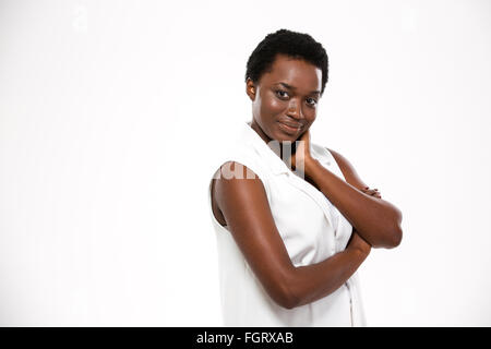 Affascinante felice americano africano giovane donna in piedi con le mani incrociate su sfondo bianco Foto Stock