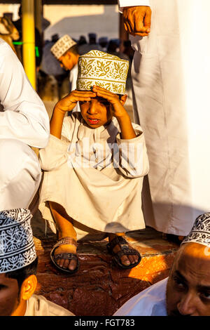 Un giovane ragazzo in abito tradizionale al venerdì mercato del bestiame, Nizwa, Ad Dakhiliyah Regione, Oman Foto Stock