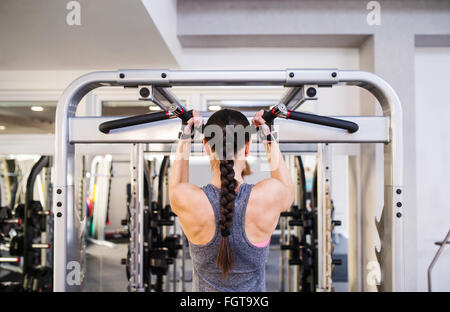 Donna in palestra flettendo muscoli della schiena sul cavo macchina Foto Stock