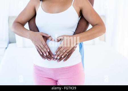 Mani messa a forma di cuore sulla pancia Foto Stock