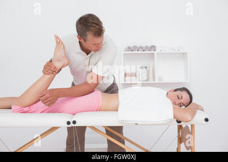 Fisioterapista facendo massaggio delle gambe al suo paziente Foto Stock