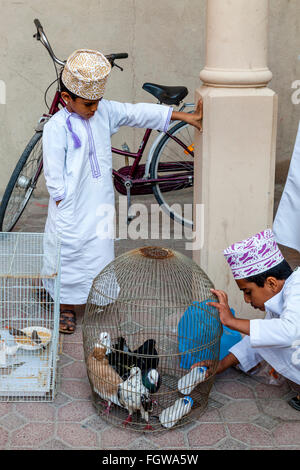 Un ragazzo Omani vende uccelli esotici al venerdì mercato di uccelli, Nizwa, Ad Dakhiliyah Regione, Oman Foto Stock