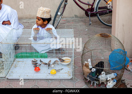 Un ragazzo Omani vende uccelli esotici al venerdì mercato di uccelli, Nizwa, Ad Dakhiliyah Regione, Oman Foto Stock