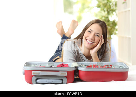 Donna felice pianificando un viaggio preparare una valigia e guardando la fotocamera Foto Stock