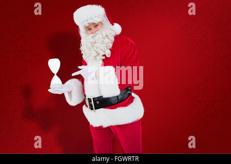 Immagine composita di sorridere santa claus azienda clessidra Foto Stock