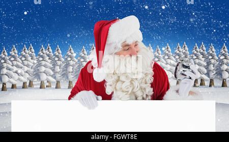 Immagine composita di felice santa tenendo sveglia e firmare Foto Stock