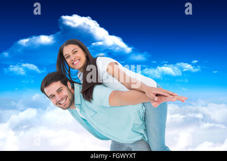 Immagine composita di felice uomo informale dando bella ragazza piggy back Foto Stock