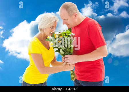 Immagine composita di uomo maturo che offre il suo partner fiori Foto Stock