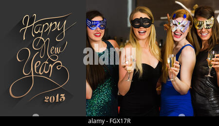 Immagine composita di ridere amici indossando maschere azienda bicchieri da champagne Foto Stock