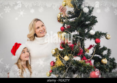 Immagine composita di festosa madre e figlia decorare albero di natale Foto Stock