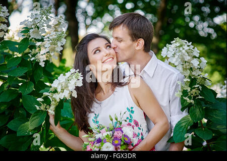 Elegante lo sposo con la sua sposa felice baci nel parco Foto Stock