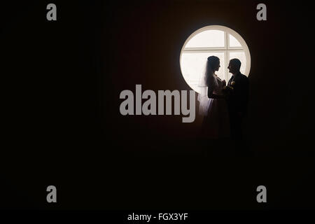 Silhouette di una sposa e lo sposo sullo sfondo della finestra Foto Stock