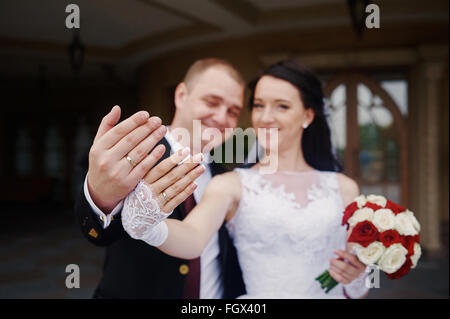 Felice sposa e lo sposo che mostra i loro anelli sulle mani Foto Stock