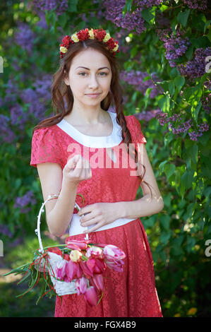Giovane donna con corona e con fiori lilla in primavera Foto Stock