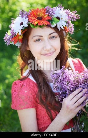 Giovane donna con corona e con fiori lilla in primavera Foto Stock