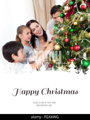 Immagine composita della famiglia felice decorazione di un albero di natale con boubles Foto Stock