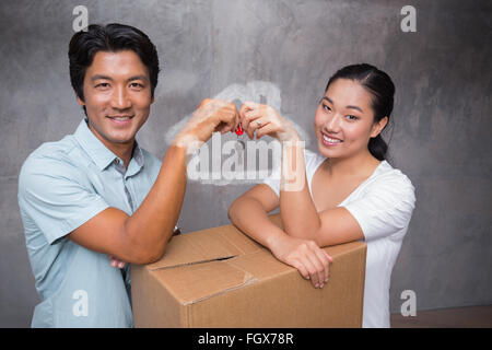 Immagine composita della coppia felice azienda chiave di casa e appoggiato sulla scatola di movimentazione Foto Stock