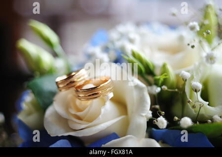 Oro due anelli di nozze giacciono su una rosa bianca Foto Stock