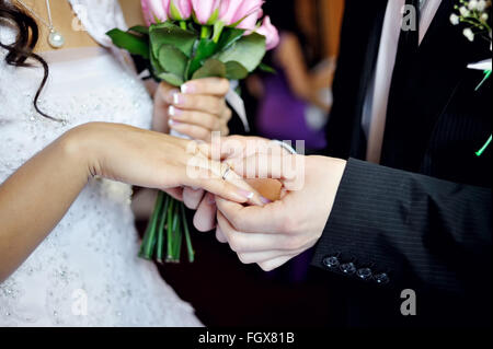 Lo sposo mettendo sulla cerimonia di nozze per la sposa anello d'oro al dito Foto Stock