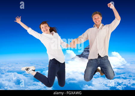 Immagine composita del giovane di salto e tenendo le mani Foto Stock