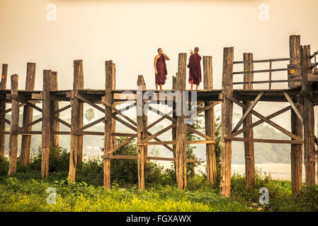 Due monaci buddisti prendendo fotografie con il telefono cellulare sul legno storico U Bein Bridge Foto Stock