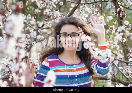 Bella felice giovane donna godendo di odore in una fioritura spring garden Foto Stock