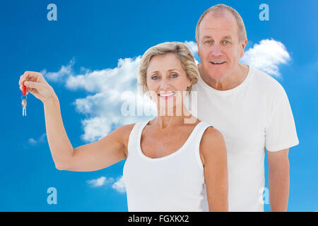 Immagine composita della coppia matura sorridente in telecamera con la nuova chiave di casa Foto Stock