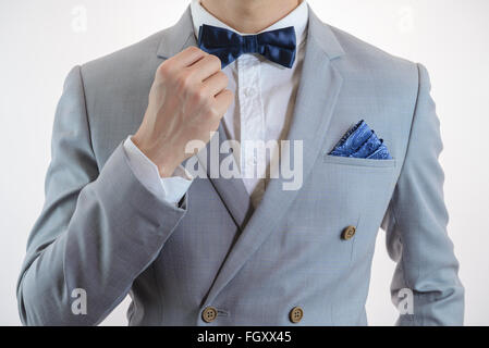 Uomo in abito grigio, plaid texture, blue bowtie e pocket Square, vicino su sfondo bianco Foto Stock