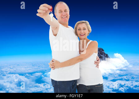 Immagine composita della coppia matura sorridente in telecamera con la nuova chiave di casa Foto Stock