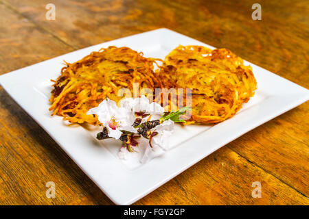 Latkes di patate servita con fiori di mandorla Foto Stock