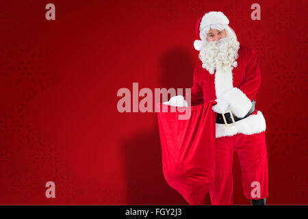 Immagine composita di sorridere santa claus sacco di apertura Foto Stock