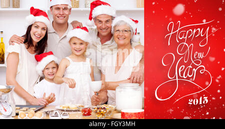 Immagine composita dei bambini la cottura i dolci di natale in cucina con la loro famiglia Foto Stock