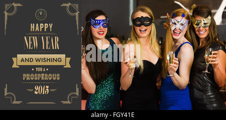 Immagine composita di ridere amici indossando maschere azienda bicchieri da champagne Foto Stock