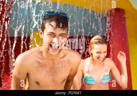 Matura in tute swimmning sotto gli spruzzi di una fontana. Il calore d'estate. Foto Stock