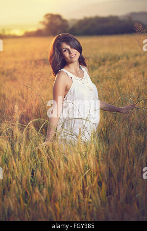 Bella donna pone in un campo al tramonto. Stagione estiva ritratto