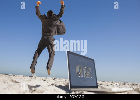 Immagine composita di imprenditore vittorioso jumping lasciando il suo computer portatile Foto Stock