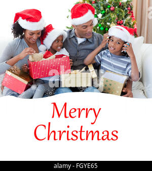 Immagine composita della famiglia felice a giocare con i regali di natale Foto Stock