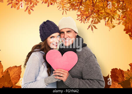 Immagine composita della coppia felice in un abbigliamento caldo cuore di contenimento Foto Stock