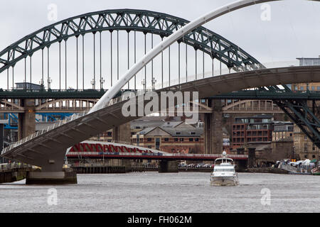 Una nave da diporto vele verso il basso del Tyne come il Gateshead Millennium Bridge viene sollevata con il Tyne Bridge in background Foto Stock