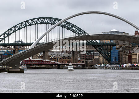 Una nave da diporto vele verso il basso del Tyne come il Gateshead Millennium Bridge viene sollevata con il Tyne Bridge in background Foto Stock