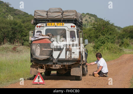 Vecchia Land Rover Defender a passo lungo nel Parco Nazionale del Serengeti in Tanzania. Guasto Foto Stock