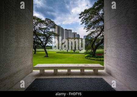Memorial Wall e vista di lontani gli edifici moderni a Manila American Cemetery & Memorial, in Taguig, Metro Manila, Phil Foto Stock
