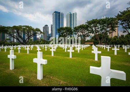 Tombe e moderni edifici di distanza al Manila American Cemetery & Memorial, in Taguig, Metro Manila, Filippine Foto Stock