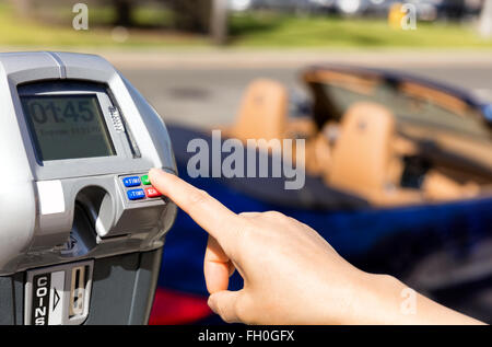 Stretta di mano femminile, dito indice, selezionando parcometro tempo all'aperto sulla strada. Foto Stock