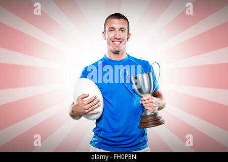 Immagine composita del ritratto di sorridere giocatore di rugby trofeo holding e la sfera Foto Stock