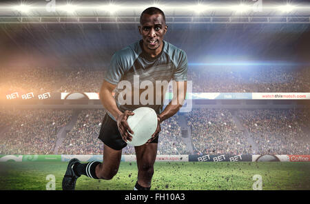 Immagine composita del ritratto di determinata sportivo in esecuzione con la palla da rugby Foto Stock